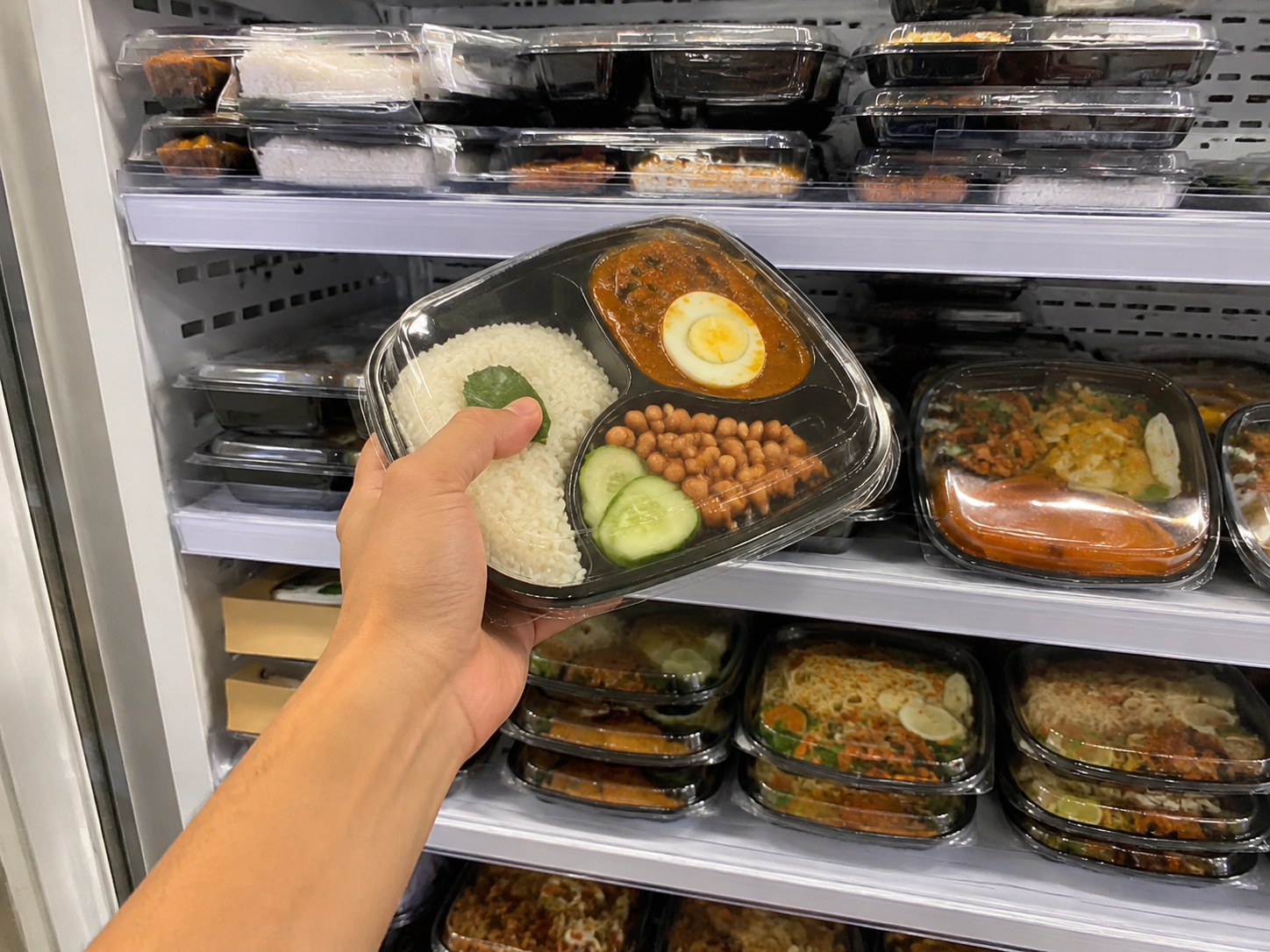 A hand reaching into a chiller full of Foodplus meals